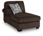Chocolate-brown corner chaise with striped throw pillow and padded armrest
