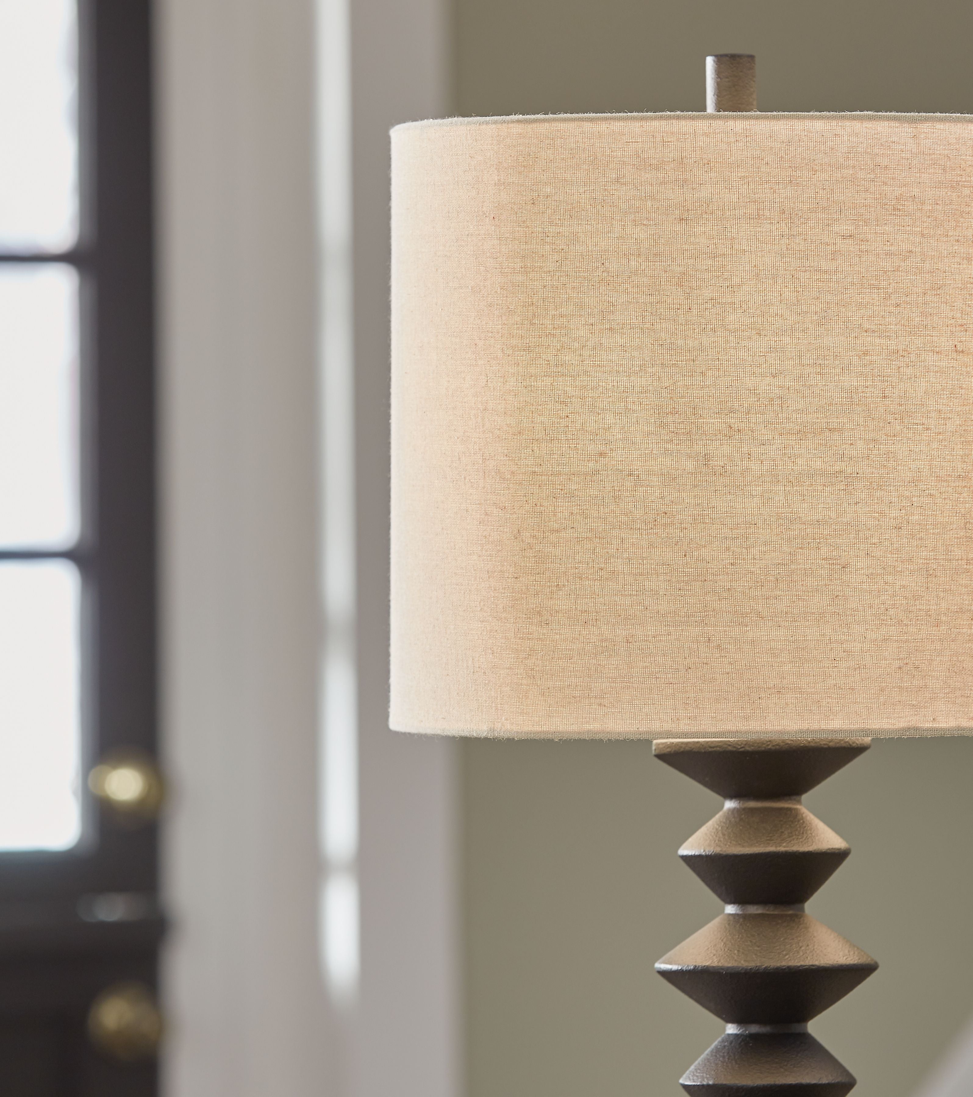 Beige drum shade on black poly buffet lamp with stacked base