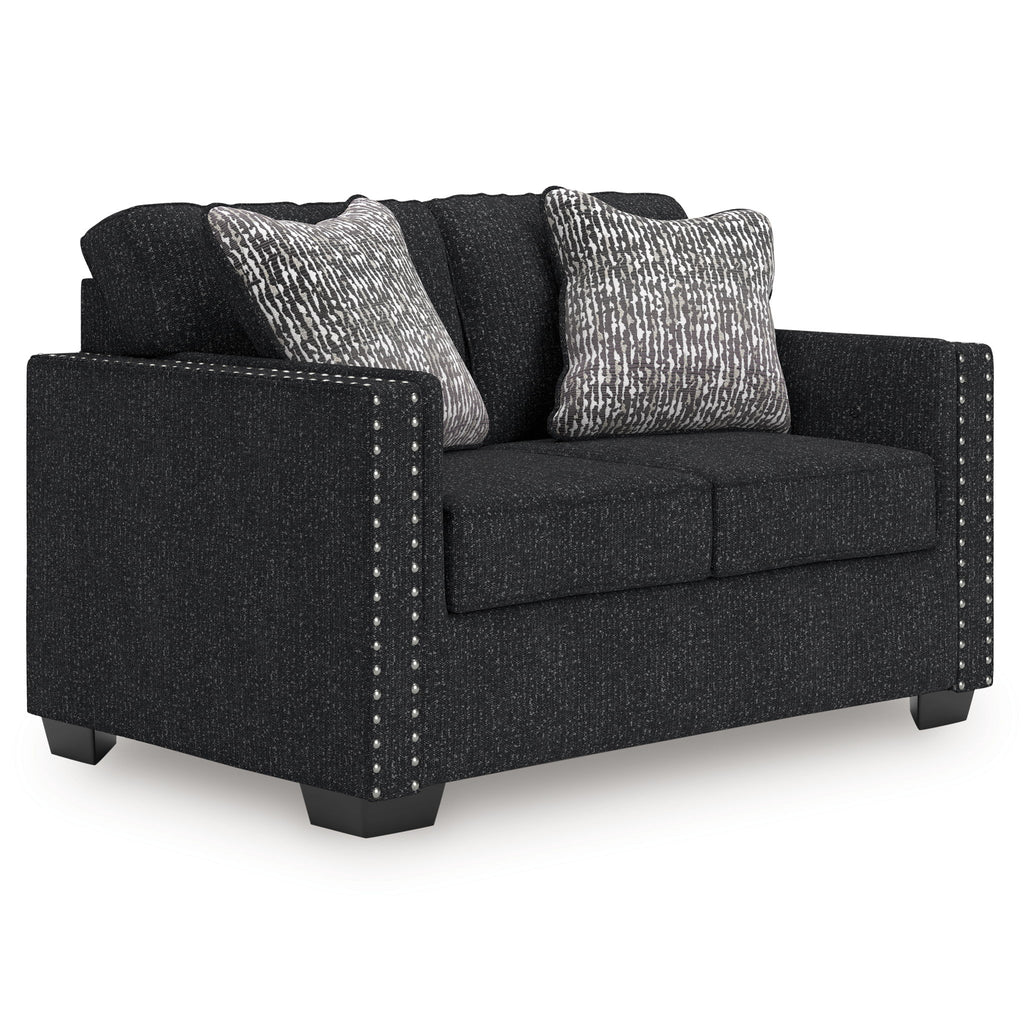 Charcoal loveseat with two patterned throw pillows, dark cushions, and nailhead side trim
