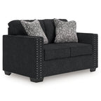 Charcoal loveseat with two patterned throw pillows, dark cushions, and nailhead side trim