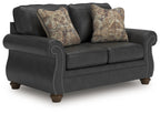 Dark gray sofa with rolled arms, tufted trim, and two patterned throw pillows