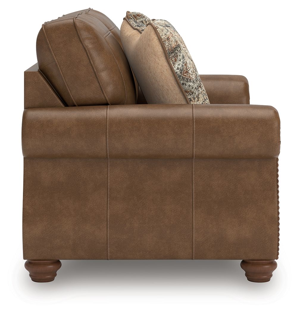 Brown loveseat with two patterned throw pillows on the backrest
