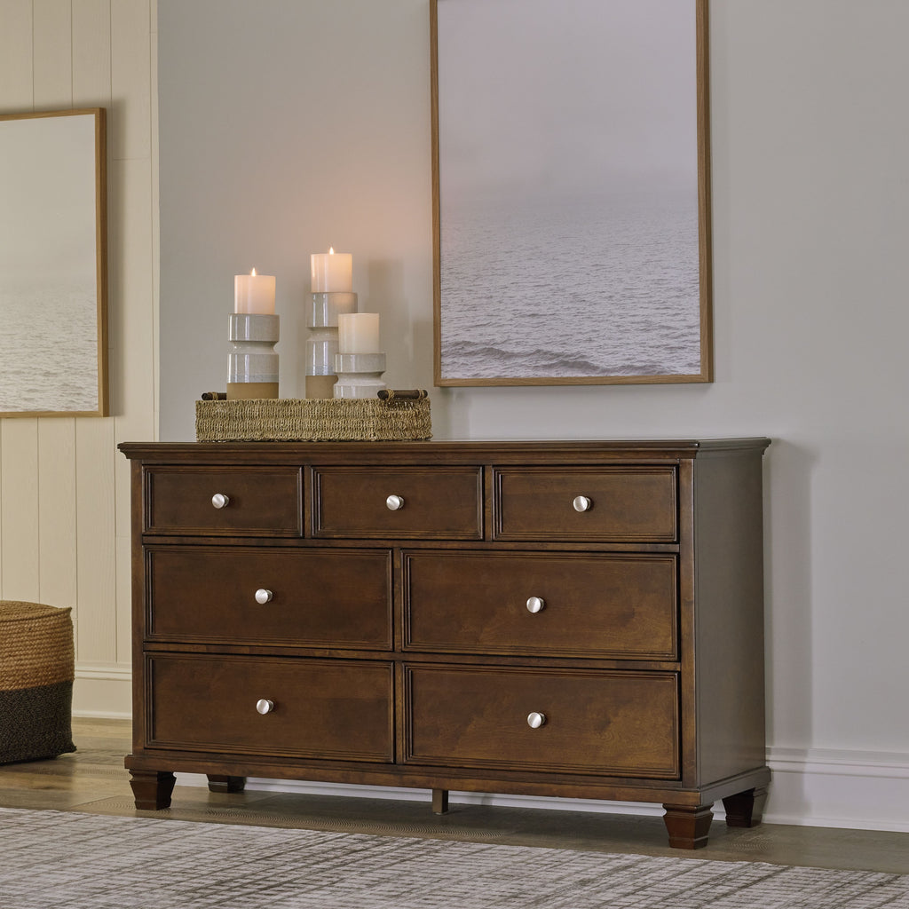Brown dresser with six drawers and round knobs, bun feet at base