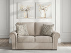Beige loveseat with rolled arms and patterned throw pillows