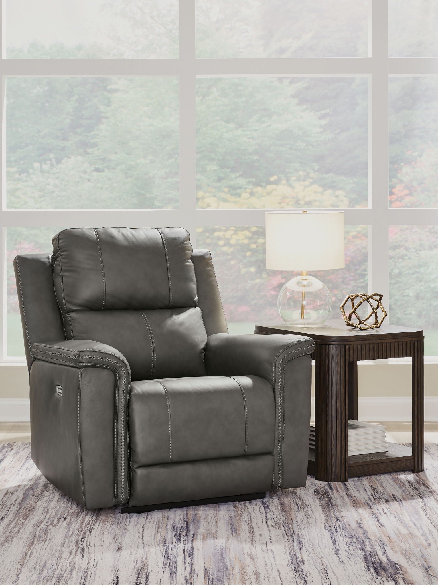 Dark gray power recliner with adjustable headrest, cushioned arms, three-quarter view