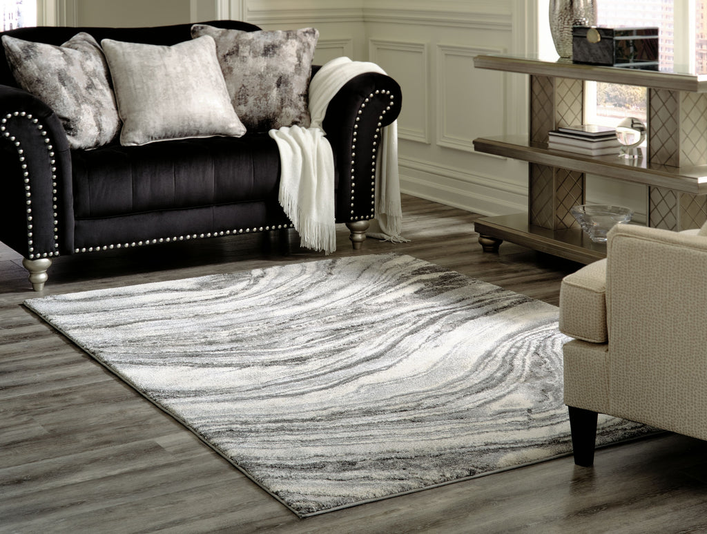 Gray and white abstract wave patterned rug lying flat on floor.