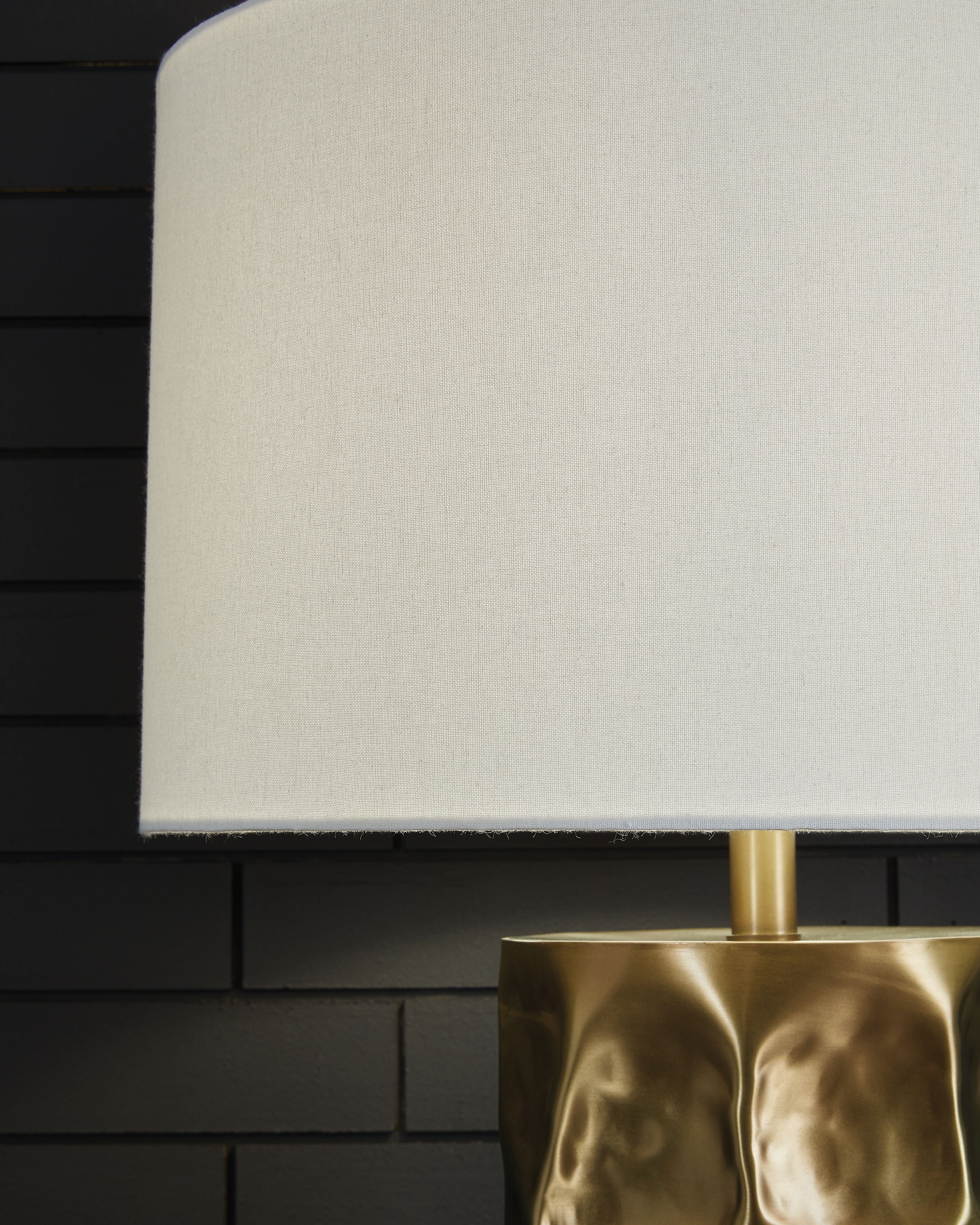 White drum shade and gold metal neck of faceted table lamp