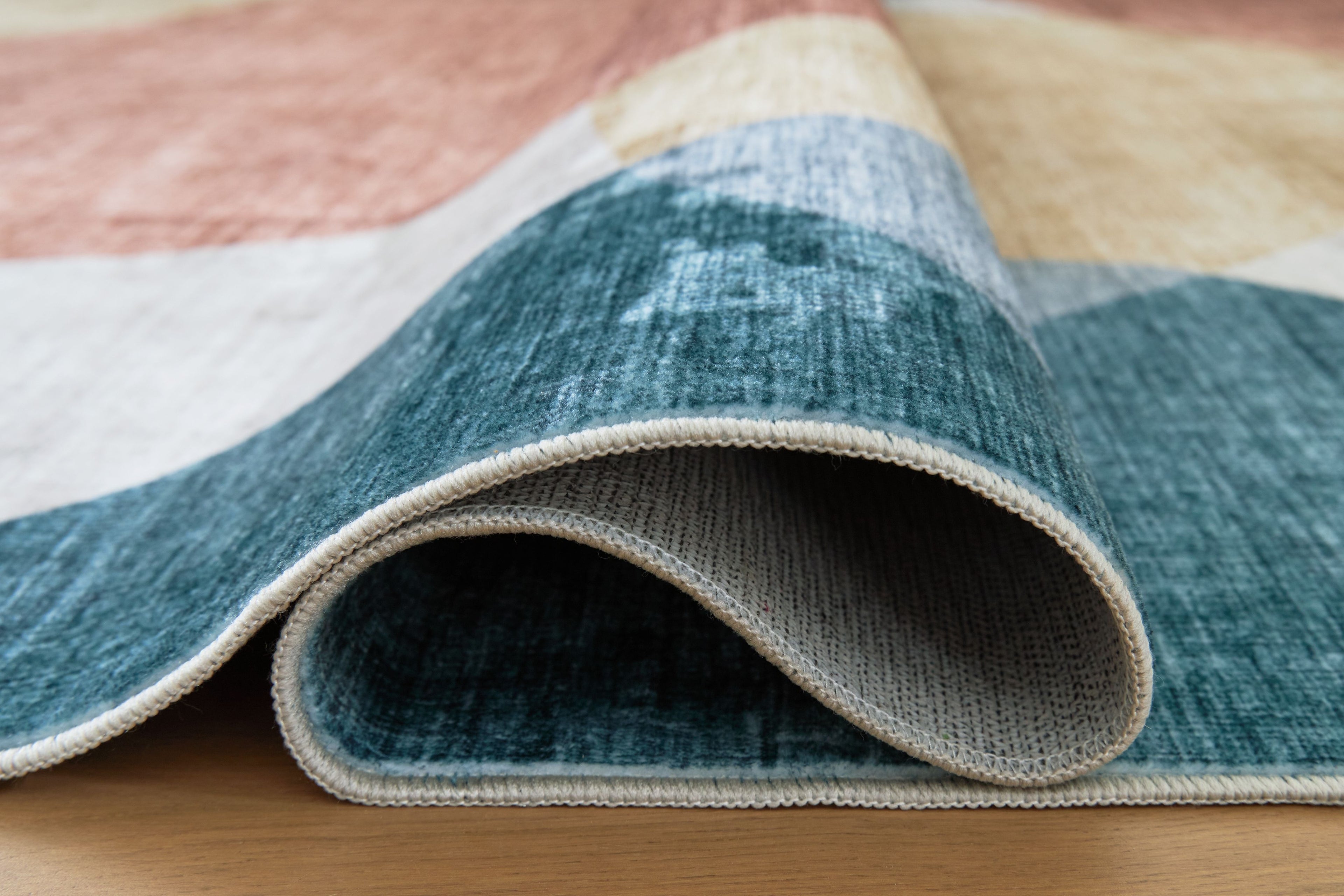 Blue washable rug with geometric pattern and light trim edge, folded view