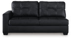 Dark sofa with tufted back, flat seat cushions, and boxy arms
