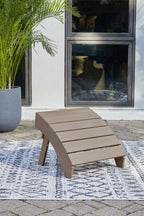 Driftwood wooden slat ottoman on ground with four legs and taupe seat.
