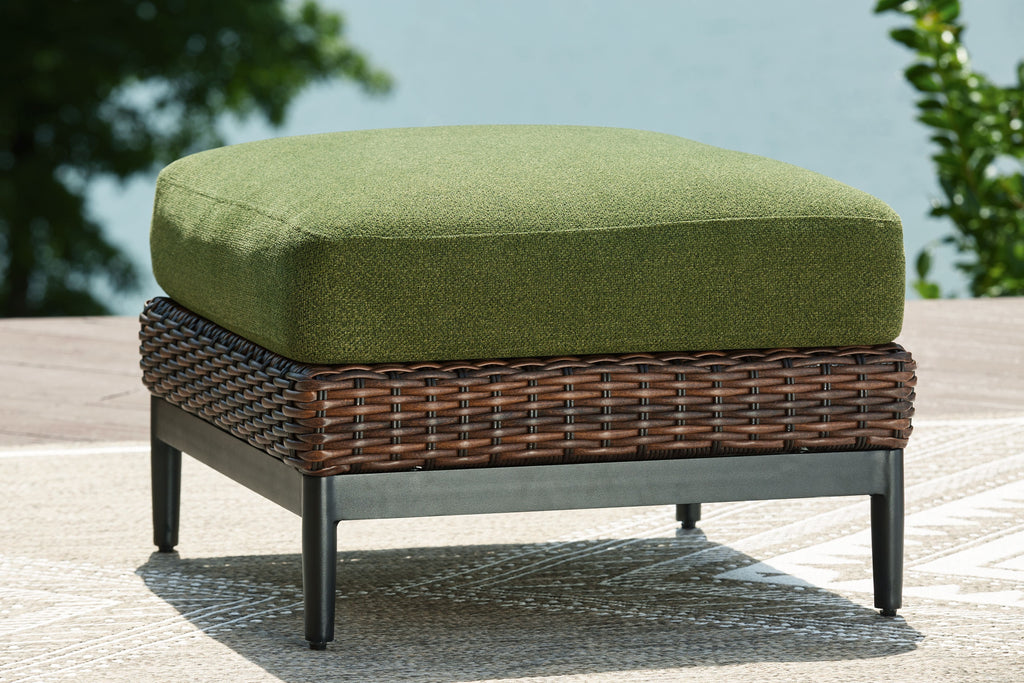 Brown wicker ottoman with green cushion and black legs