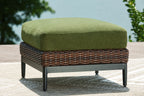 Brown wicker ottoman with green cushion and black legs