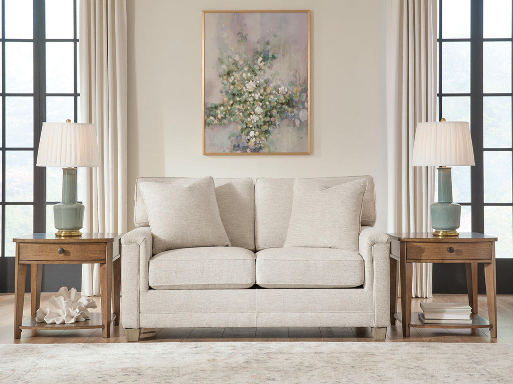 Light beige upholstered loveseat with three back pillows and dark wood feet