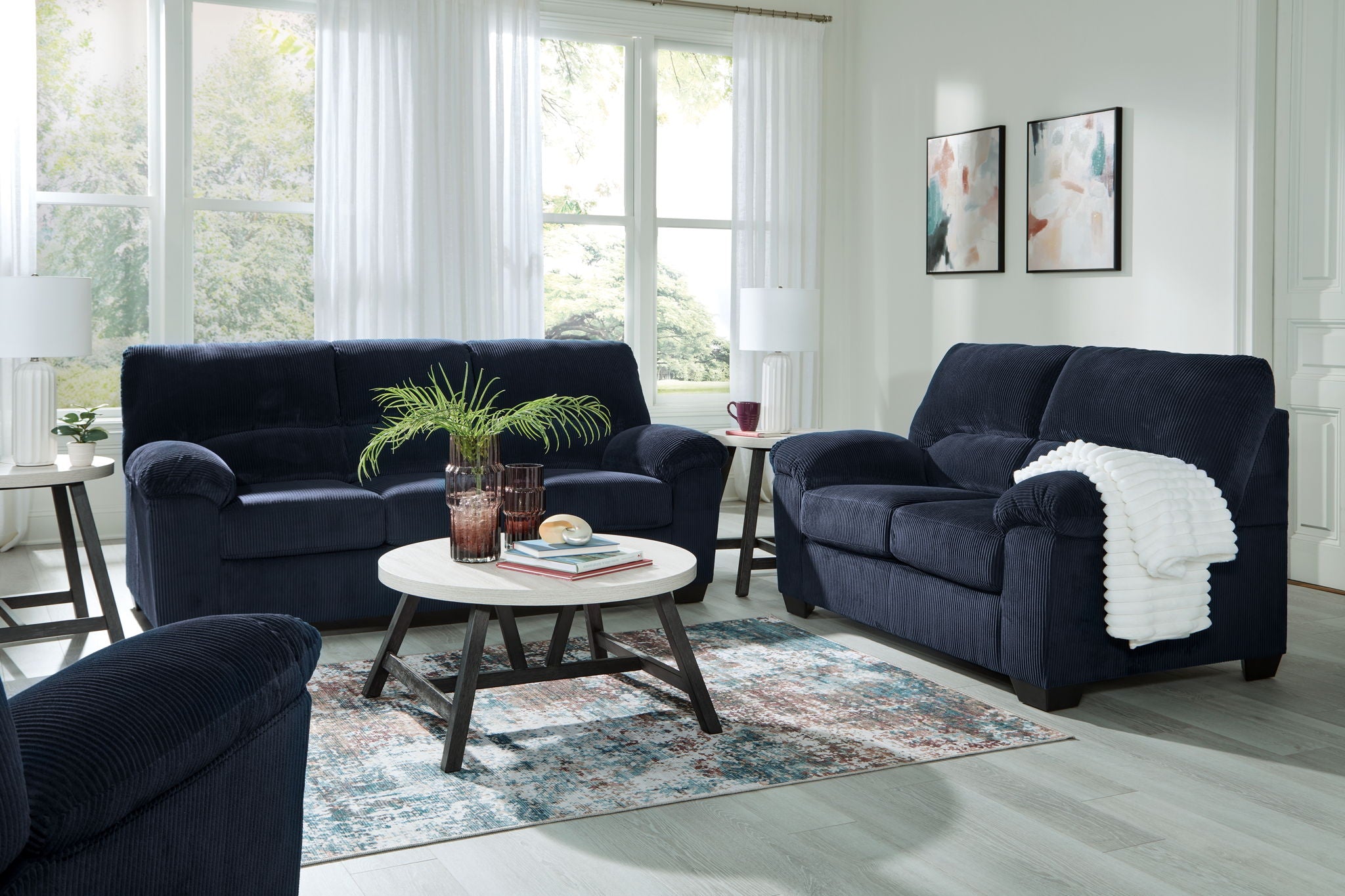 Dark blue sofa and loveseat set with matching cushions and rounded arms