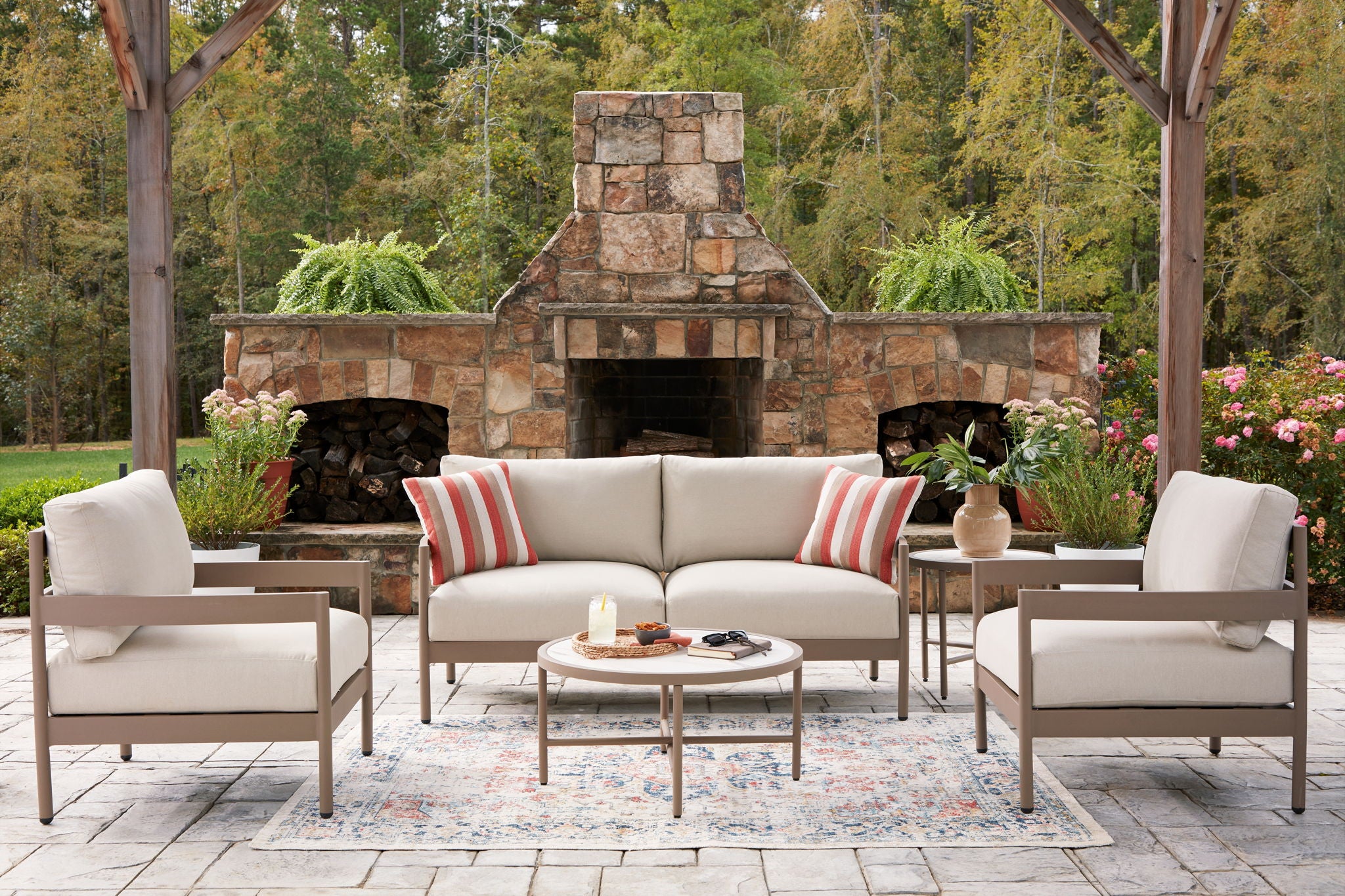 Beige outdoor seating set of 5 with loveseat, two lounge chairs, striped cushions, round table
