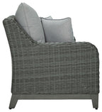 Gray wicker loveseat with tall back cushion and two pillows on the side
