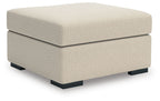 Light beige upholstered ottoman with square arms and black block feet
