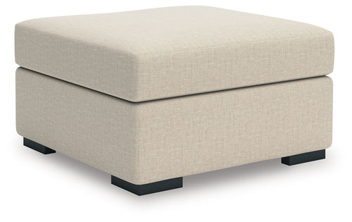 Light beige upholstered ottoman with square arms and black block feet