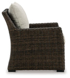 Brown wicker lounge chair with light beige back cushion and cushioned seat