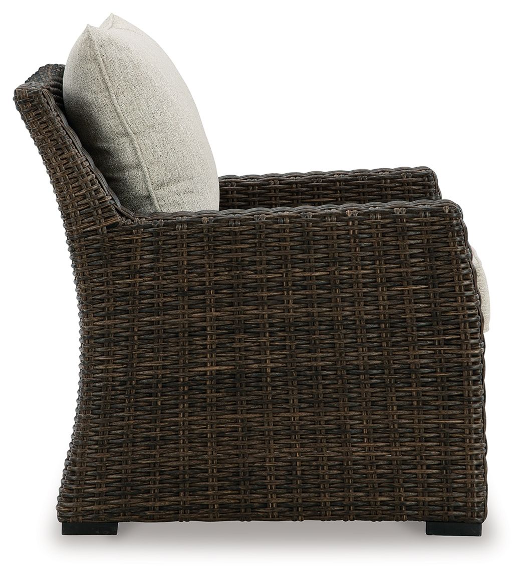Brown wicker lounge chair with light beige back cushion and cushioned seat