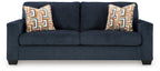 Dark navy upholstered sofa with two square patterned throw pillows.