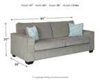 Slate stationary sofa side view with two light patterned throw pillows and angled arms