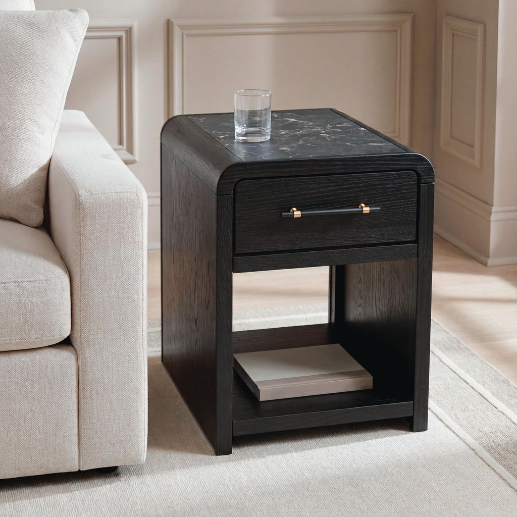 Black rectangular table with one drawer and open shelf, styled next to a sofa.