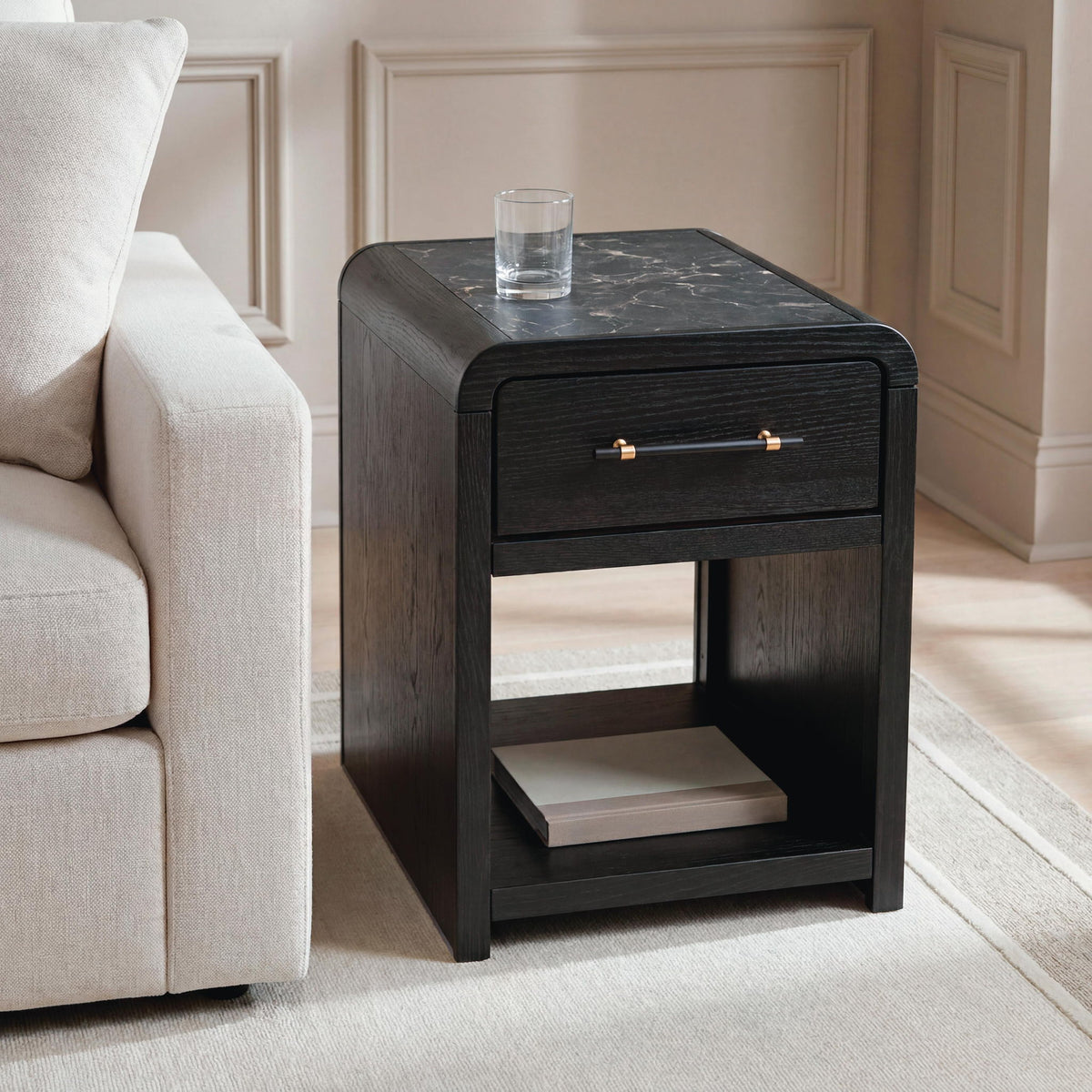 Black rectangular table with one drawer and open shelf, styled next to a sofa.