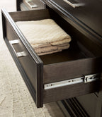 Dark grayish brown dresser drawer open with metal glides and folded beige fabric