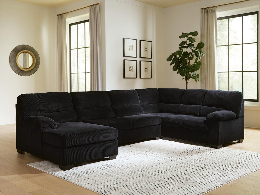 Black sectional sofa with corner chaise, tufted cushions, and lounge armrest