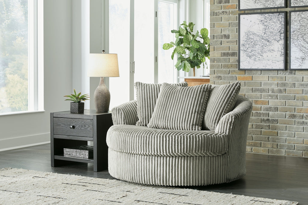 Gray oversized swivel accent chair with ribbed upholstery and three back pillows