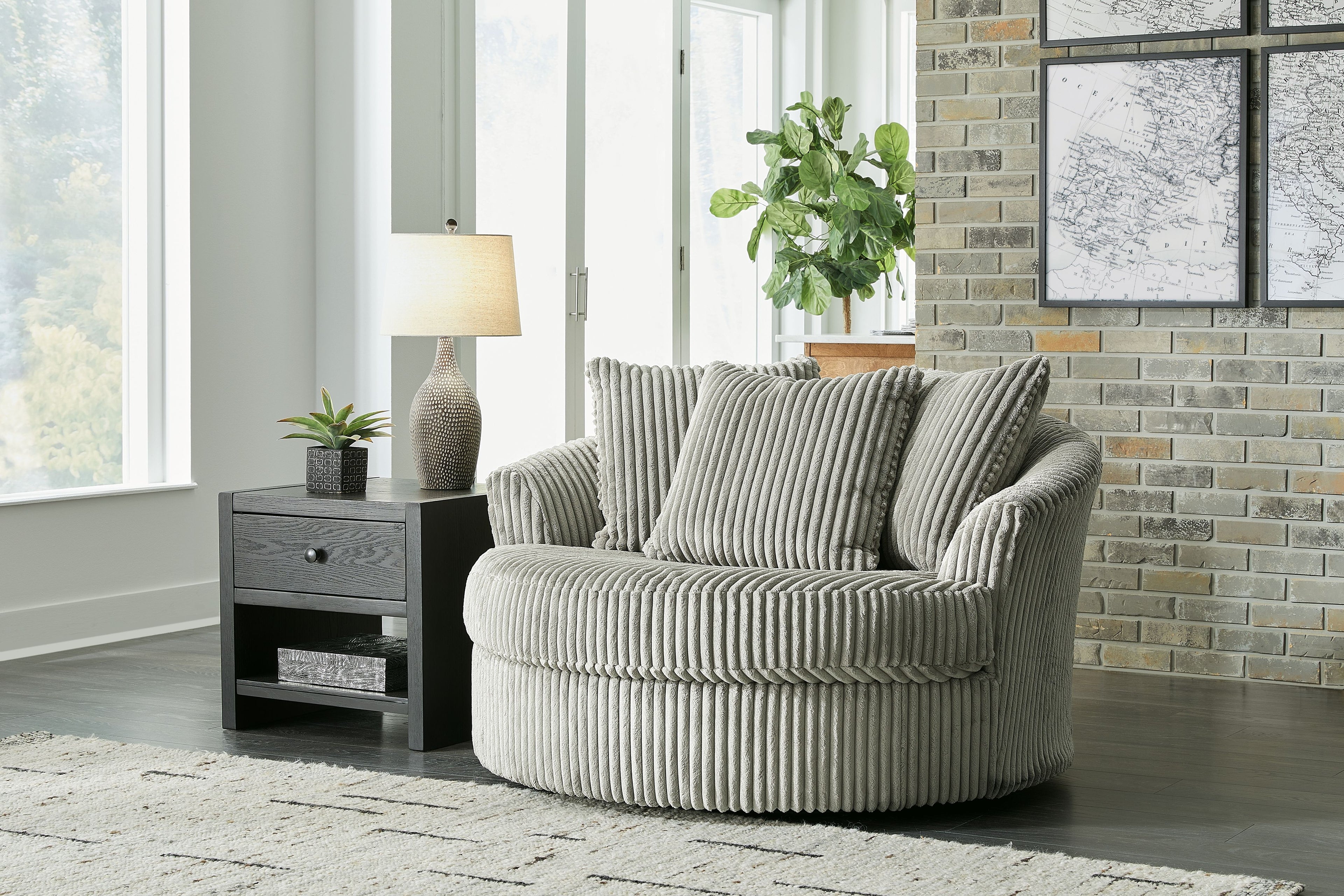 Gray oversized swivel accent chair with ribbed upholstery and three back pillows