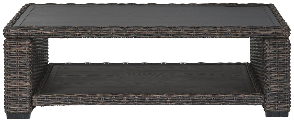 Rectangular brown wicker cocktail table with open frame and black tabletop