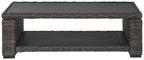 Rectangular brown wicker cocktail table with open frame and black tabletop