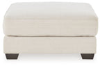 Oversized ottoman with beige fabric upholstery and dark wooden feet.