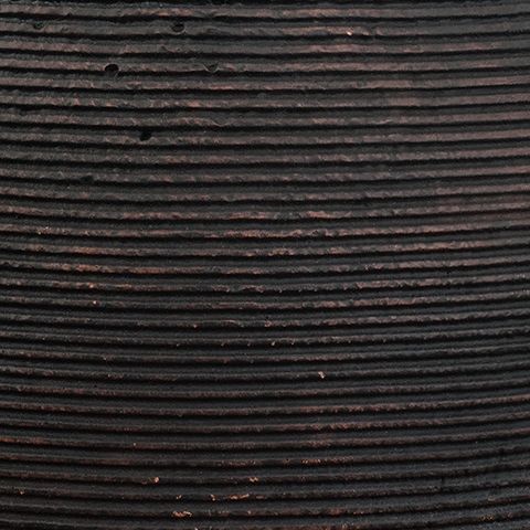 Dark vase surface close-up with horizontal ribbing and small specks