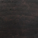 Dark vase surface close-up with horizontal ribbing and small specks
