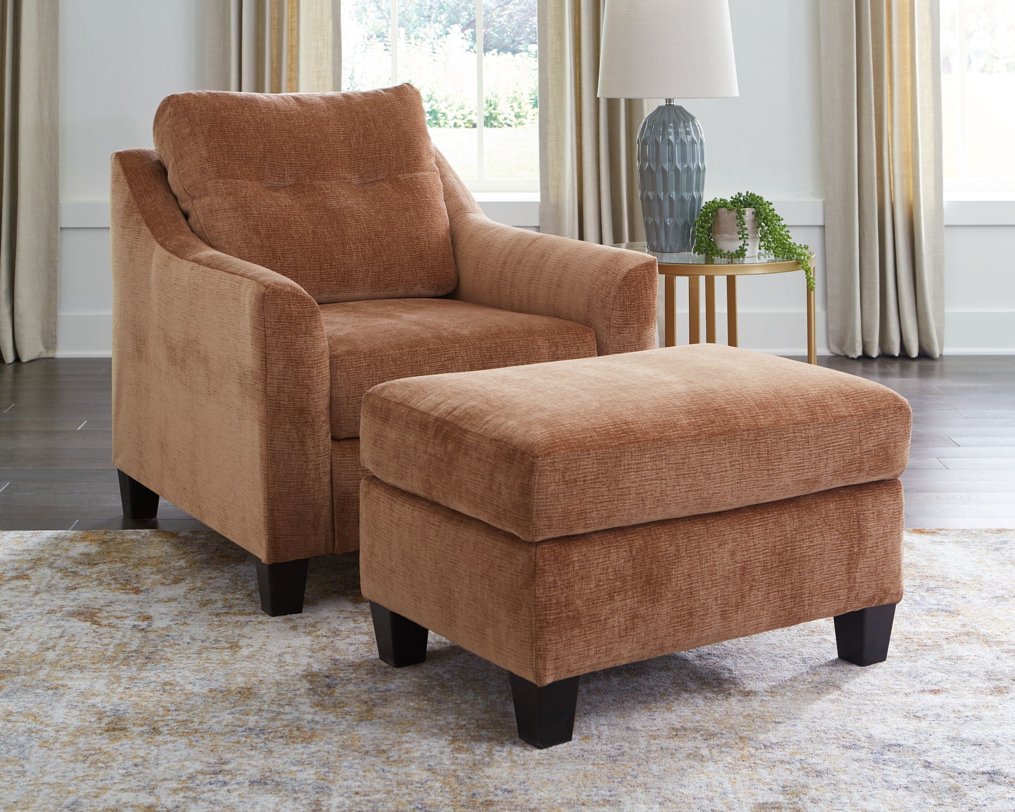 Brown upholstered accent chair set with ottoman, curved arms, and black feet