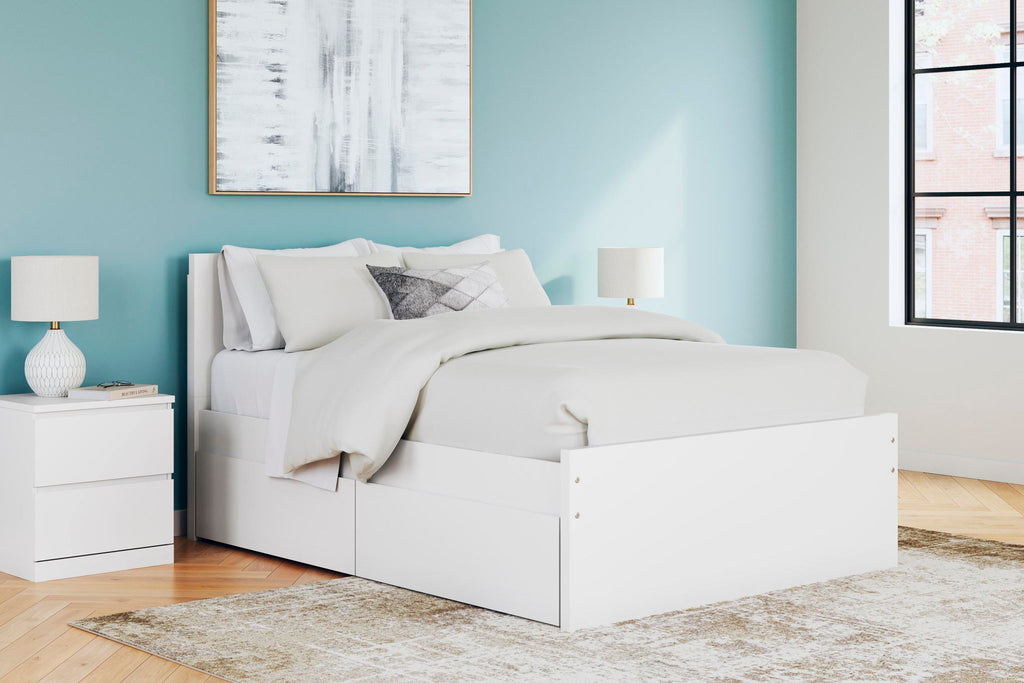 White panel platform bed with low front storage drawers and neatly styled bedding