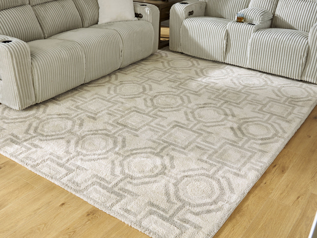 Beige area rug with repeating geometric pattern, laid in a living room corner