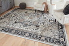 Light gray area rug with black filigree pattern panels and central medallion