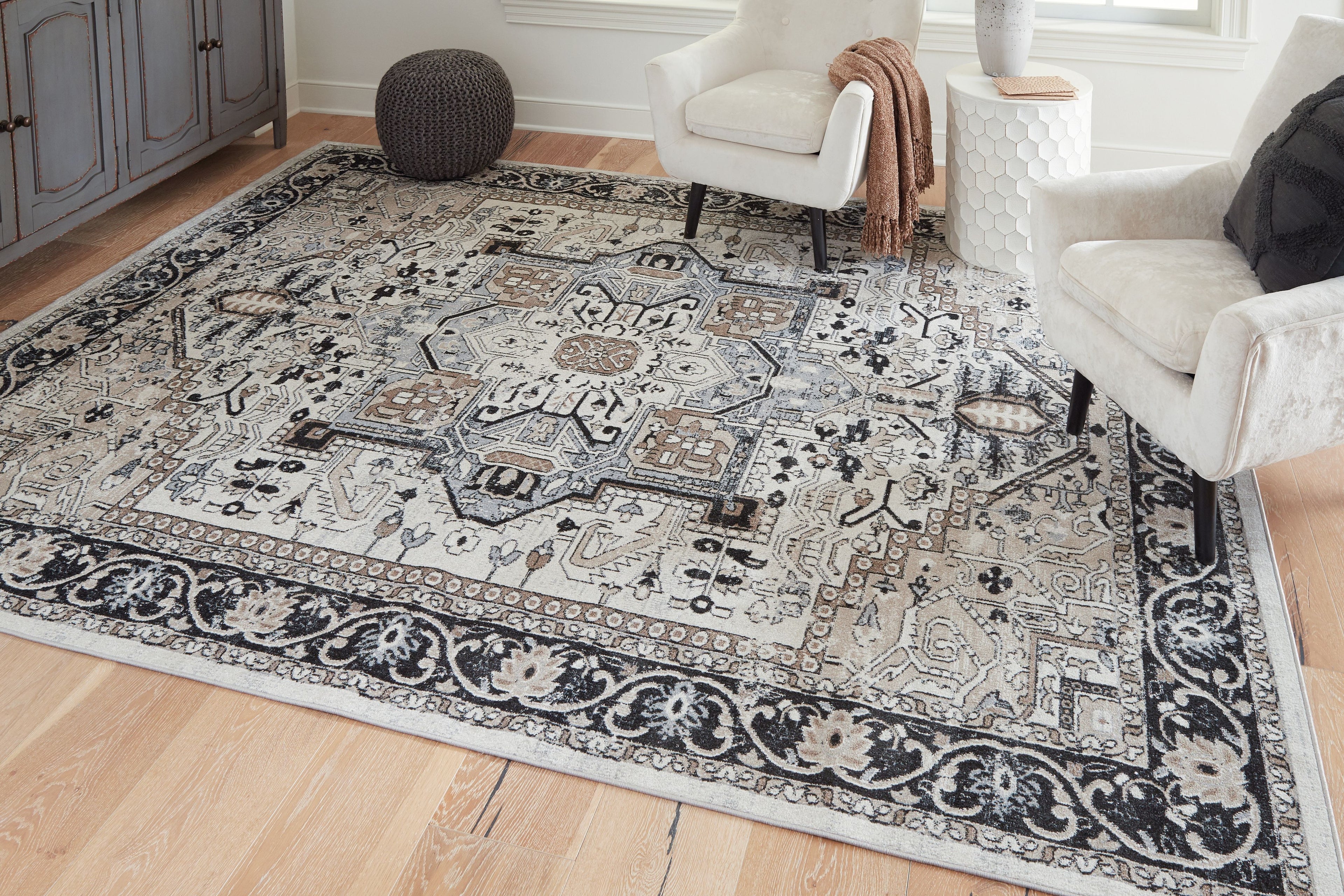 Light gray area rug with black filigree pattern panels and central medallion