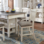 Beige dining table with white slat chairs and upholstered seats, beside a buffet