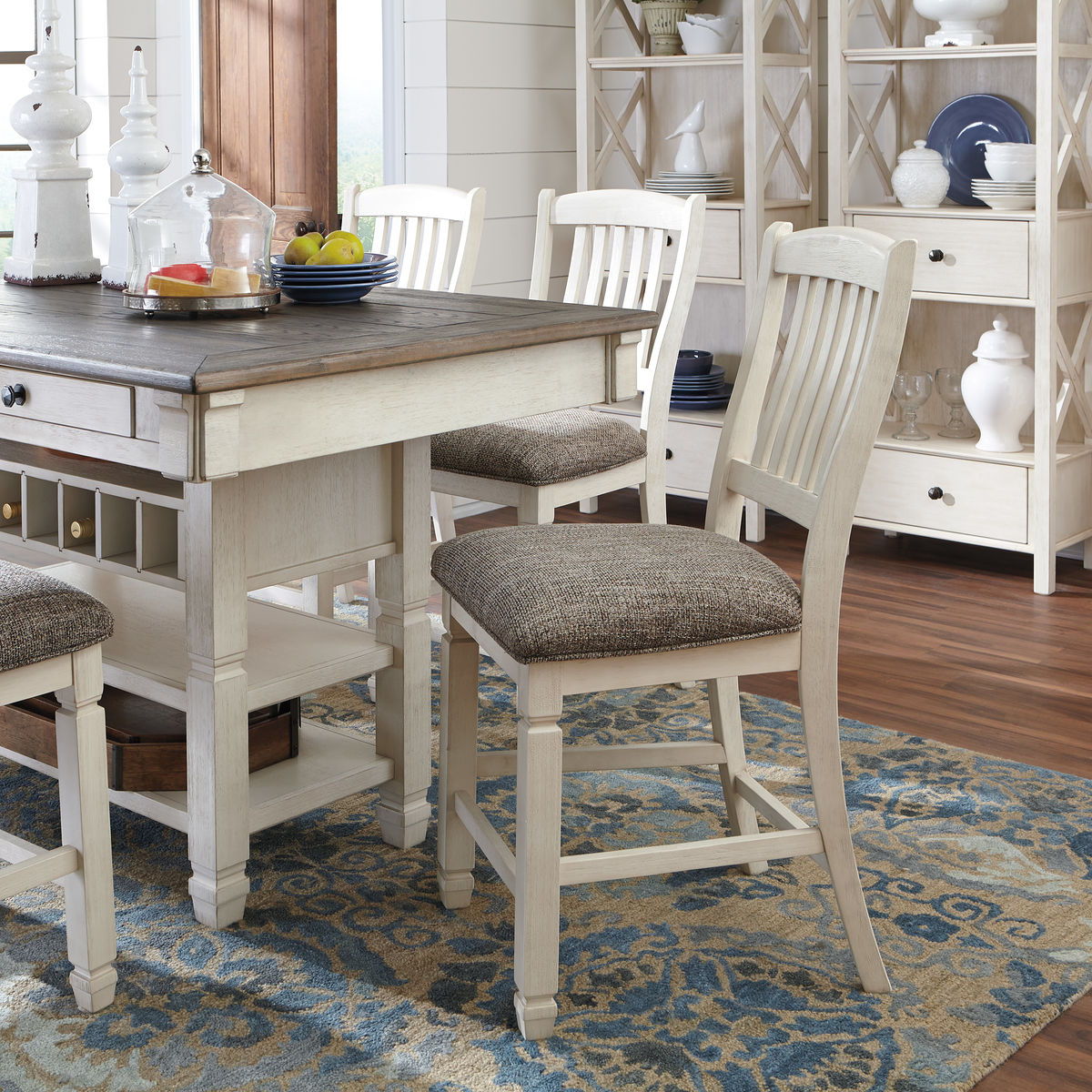 Beige dining table with white slat chairs and upholstered seats, beside a buffet