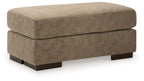 Fabric ottoman in light brown with padded top and dark wooden legs.