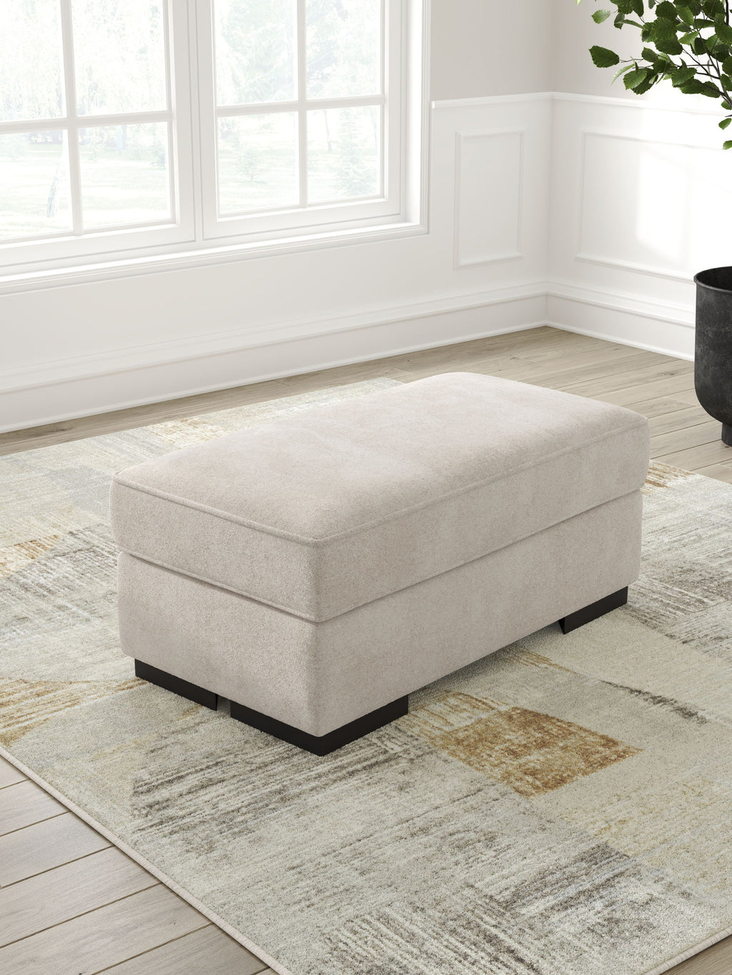 Taupe upholstered ottoman with black block legs and square top cushion