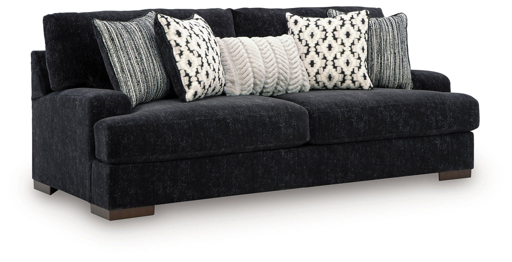 Black fabric sofa with three patterned throw pillows and two gray striped cushions