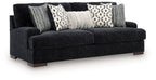 Black fabric sofa with three patterned throw pillows and two gray striped cushions