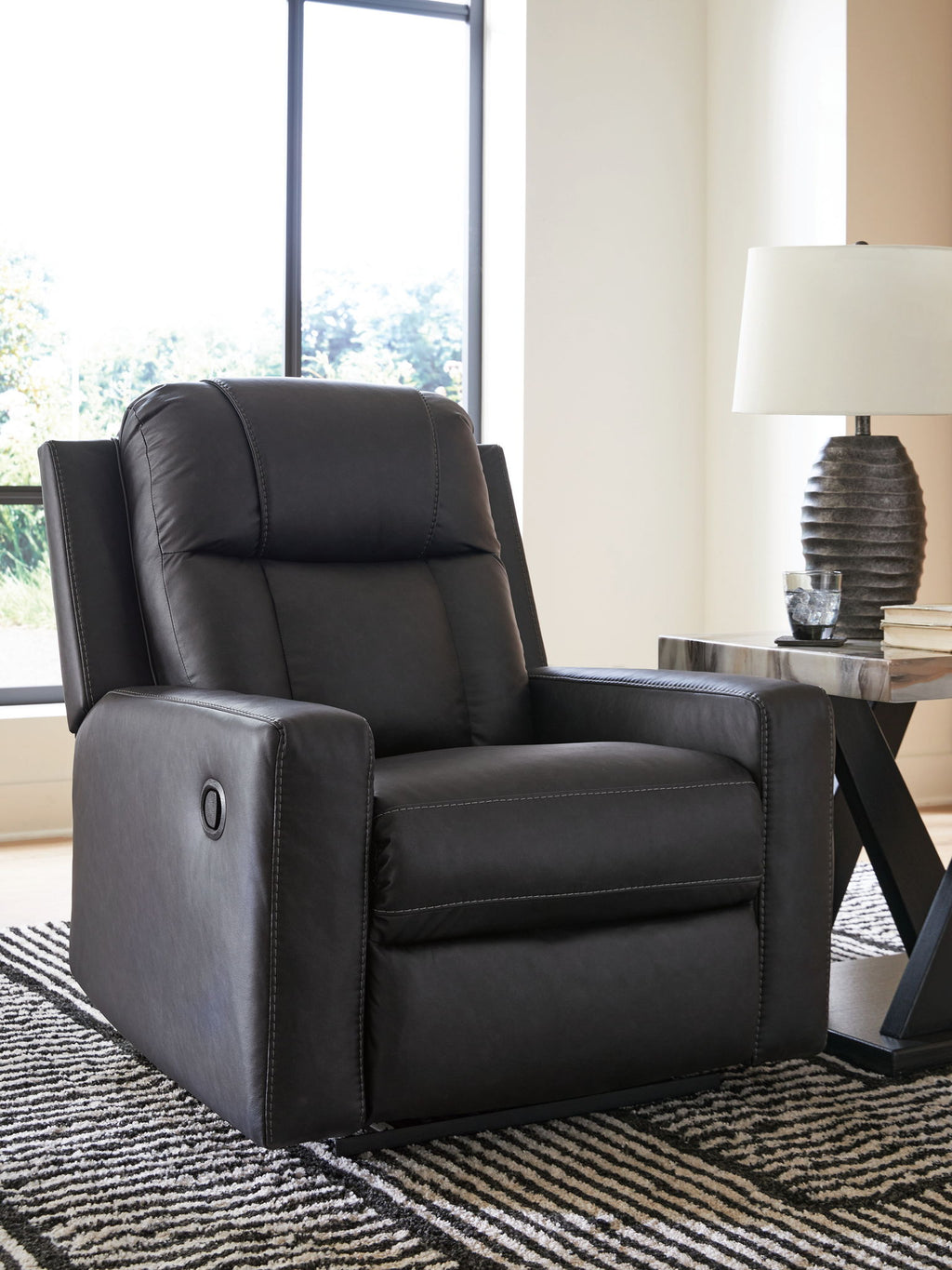 Dark charcoal zero-wall recliner with padded headrest, thick seat, and oval arm detail