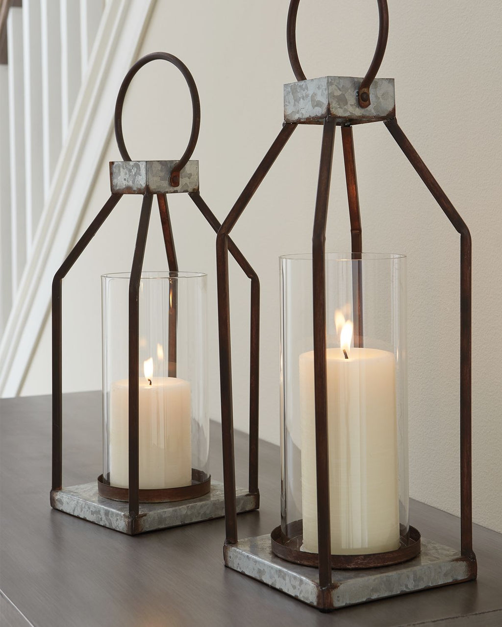 Gray/black metal lanterns with clear glass cylinders and lit candles, square stone bases (2)